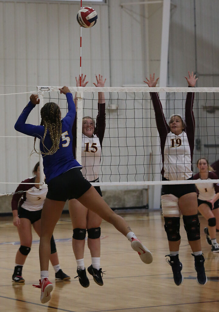 Stephens College junior Gracelyn Scott, center, and sophomore Kayley Lawson, right, jump to block a set